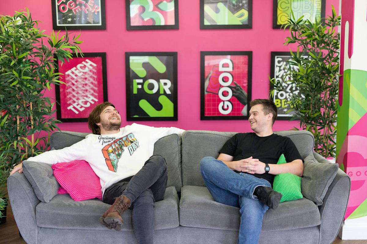 Kev and Tom talking to each other and laughing, sat on a sofa in the office.