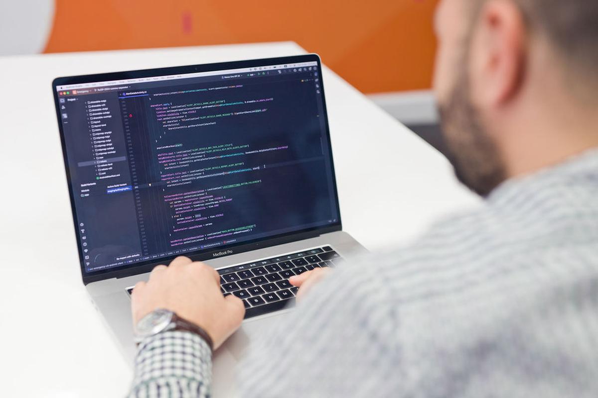 Person coding, focusing on a screen filled with colorful code lines.