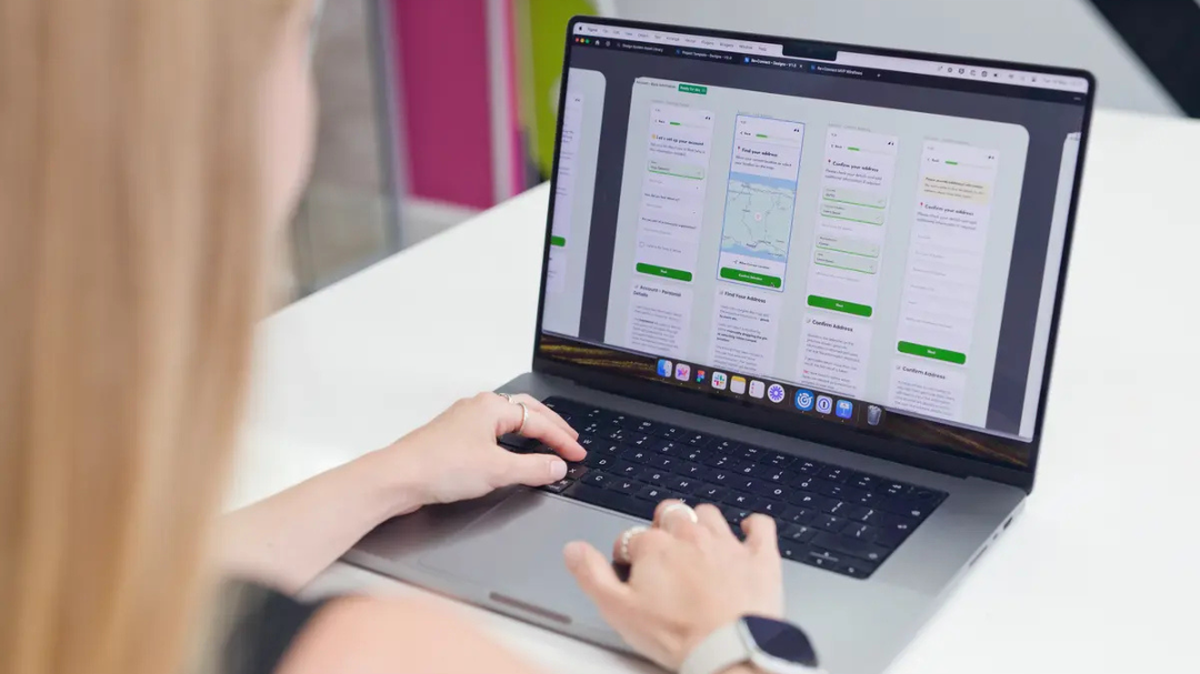 Person working on a laptop displaying web design layouts, focusing on user interface elements.