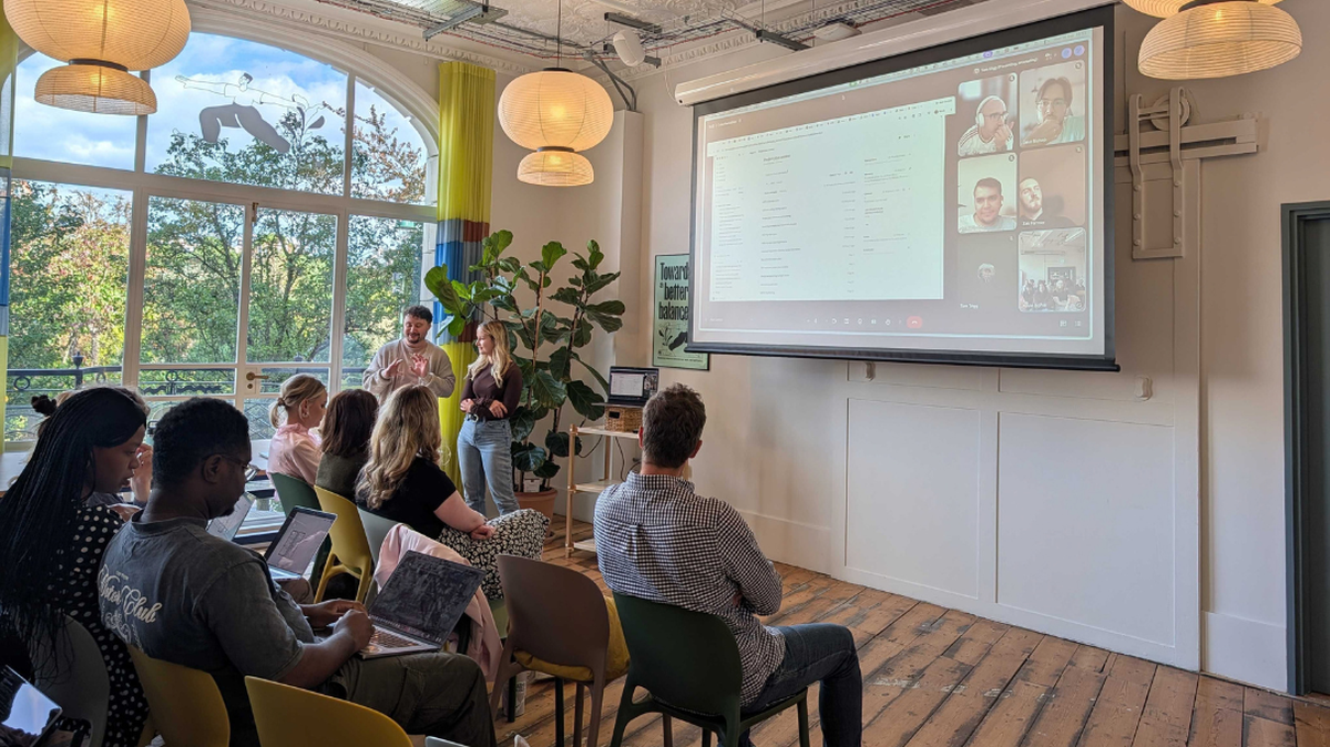 People sitting in a room watching a demonstration of a tool on a projector screen.