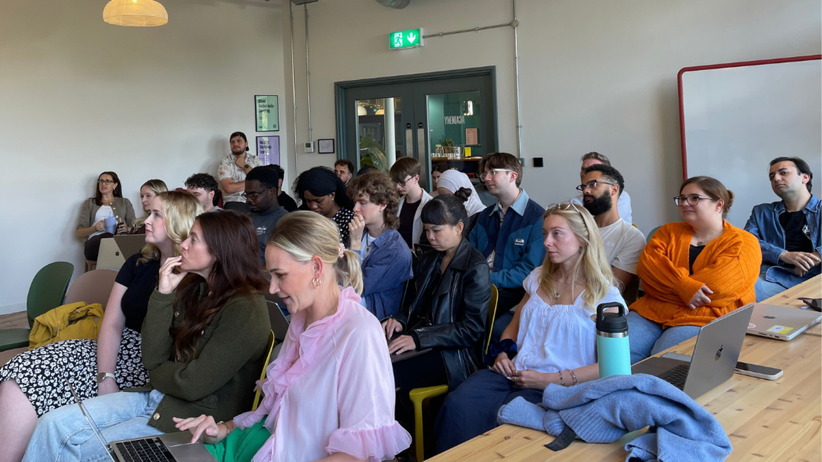 A group of people seated in a room, attentively listening to a presentation.