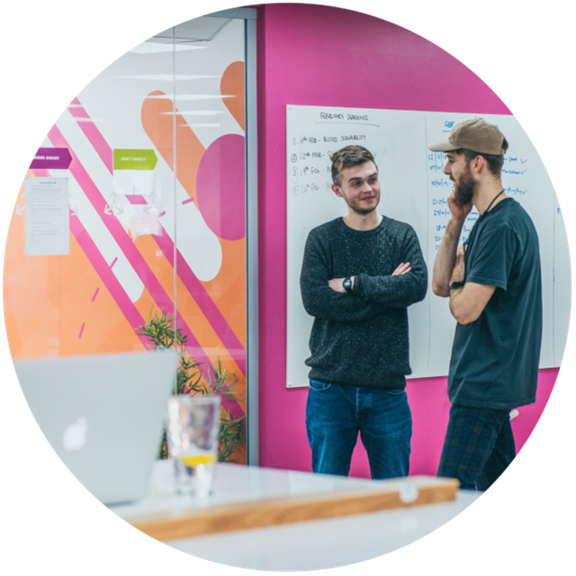 Two of the Cube team discussing a project in front of a whiteboard